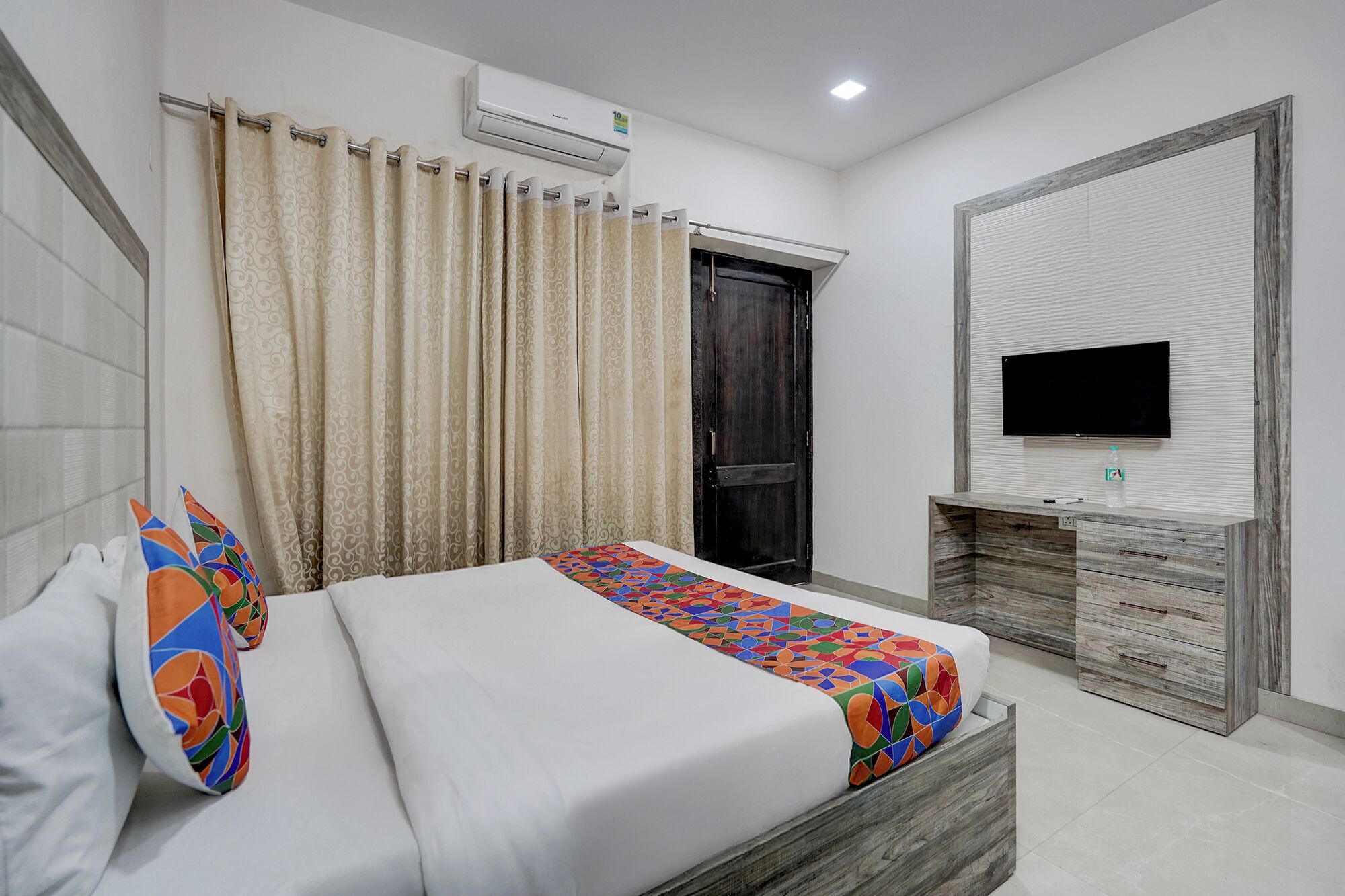 A bedroom with a bed, a TV, a wardrobe, and an air conditioner.