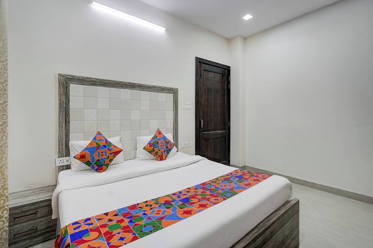A hotel room with a bed, a headboard, a door, and a patterned bed runner.