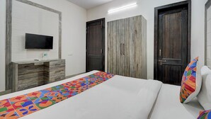 Un dormitorio con cama, televisor montado en la pared, armario y una puerta.