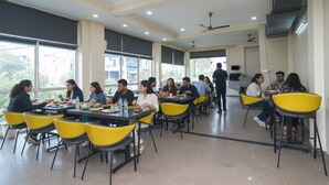 A dining area with tables and chairs, large windows, and ceiling fans. - Via Reyansh (Jaipur)
