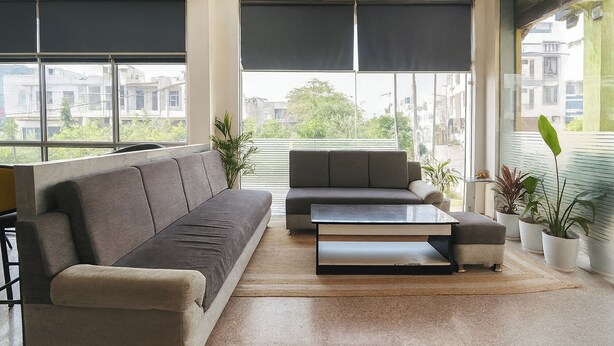 A modern living room with a sofa, a coffee table, and potted plants. - Via Reyansh (Jaipur)