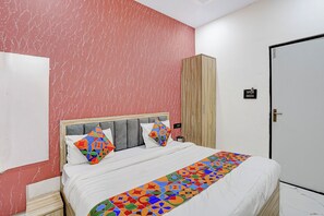 A hotel room with a bed, a wardrobe, and a door. - Fabhotel Vrrinda Residency (Varanasi)