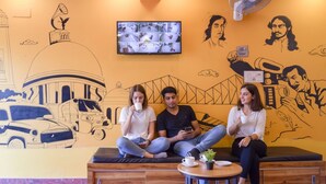Un espace détente avec une fresque murale, un téléviseur et un ventilateur.