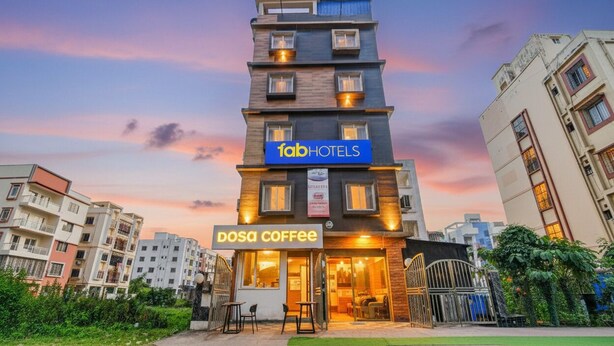 Un immeuble à plusieurs étages, avec une enseigne indiquant « fab hotels » et un café appelé « dosa coffee » situé au rez-de-chaussée.
