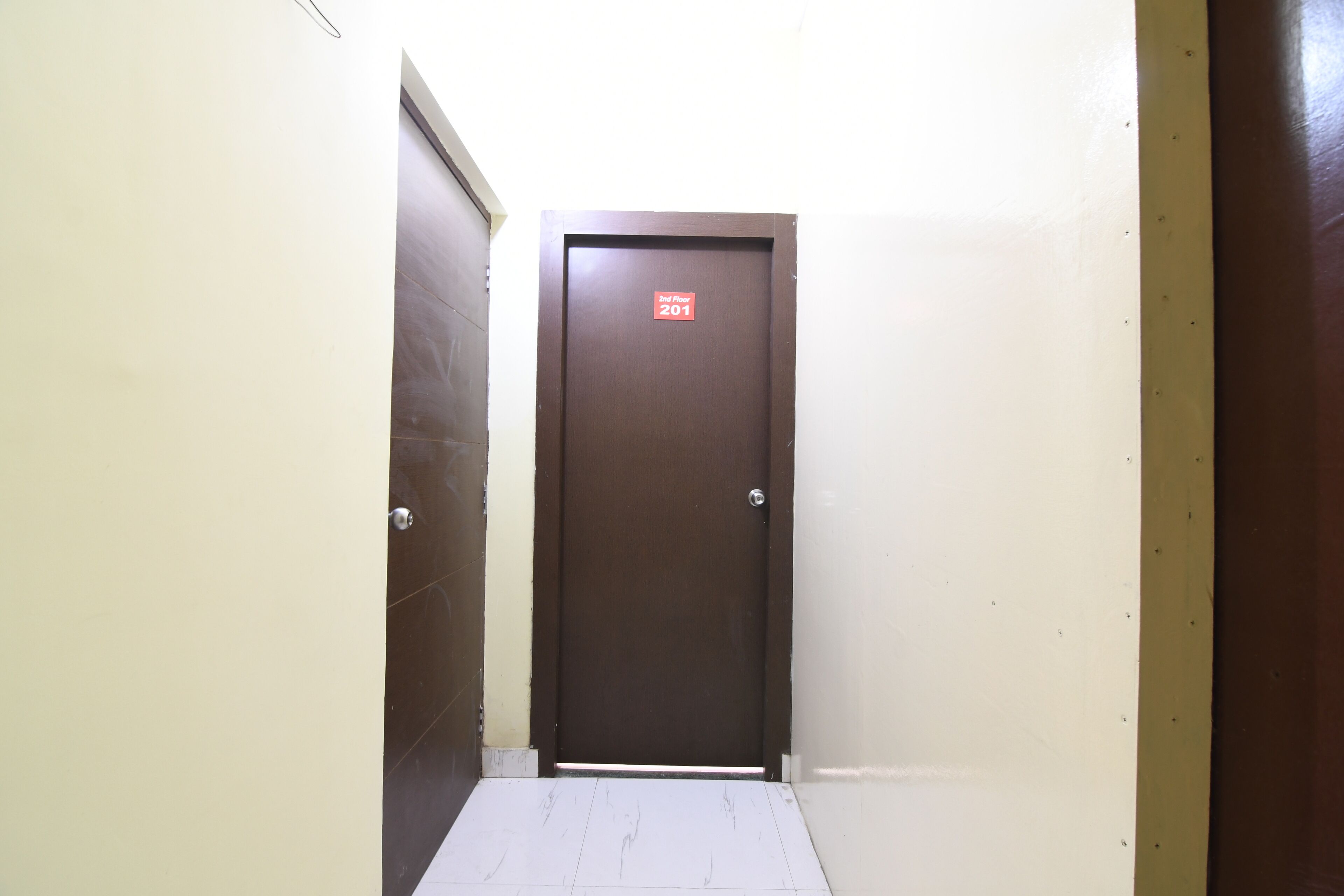 A narrow hallway with a brown door labeled "2nd Floor 201".