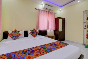 A bedroom with a bed, colorful pillows, a wardrobe, and a window with curtains. - FabHotel Bhumi Inn (Barasat)