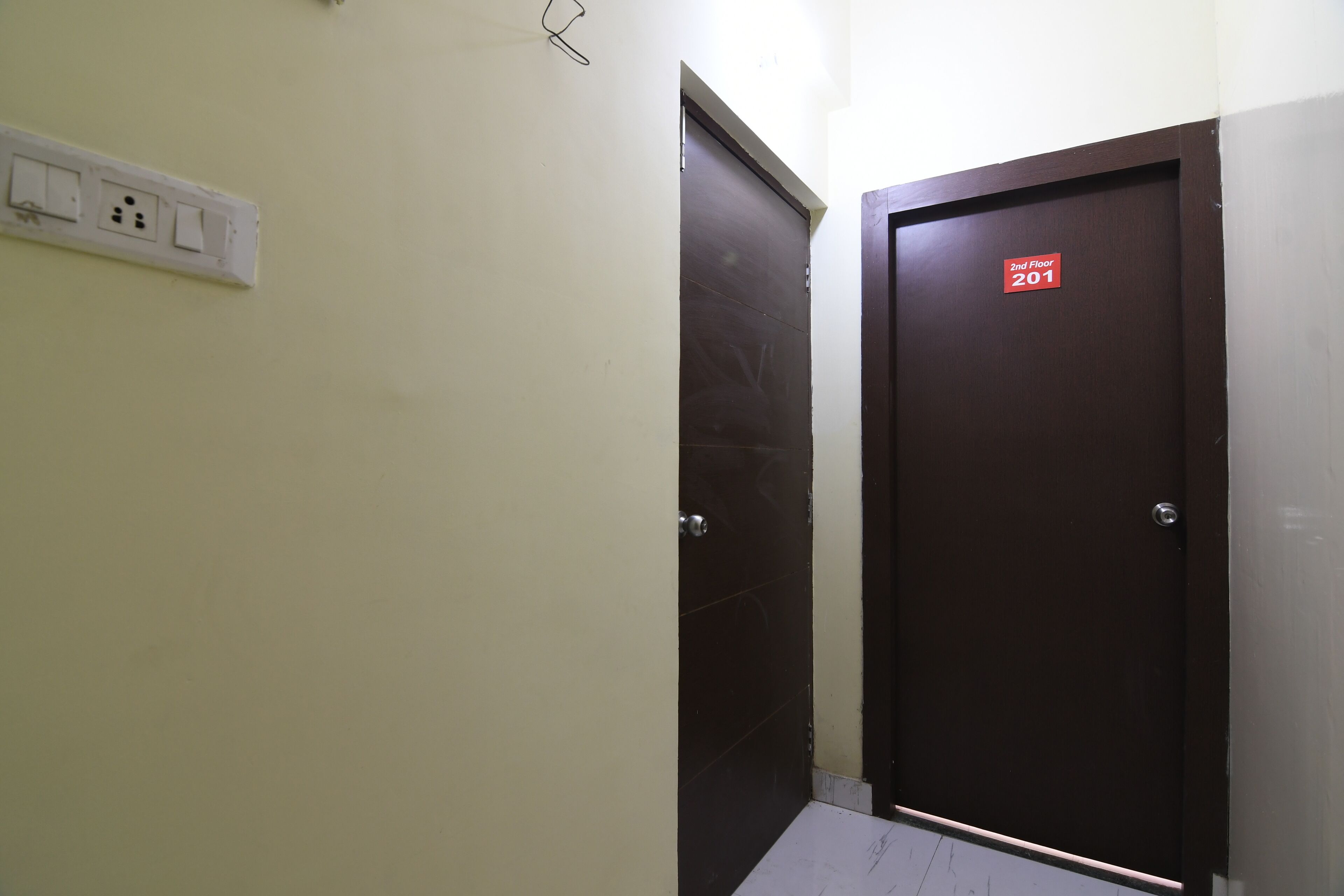 Passadís amb una porta amb la inscripció “2n Pis 201” i una presa corrent a la paret.