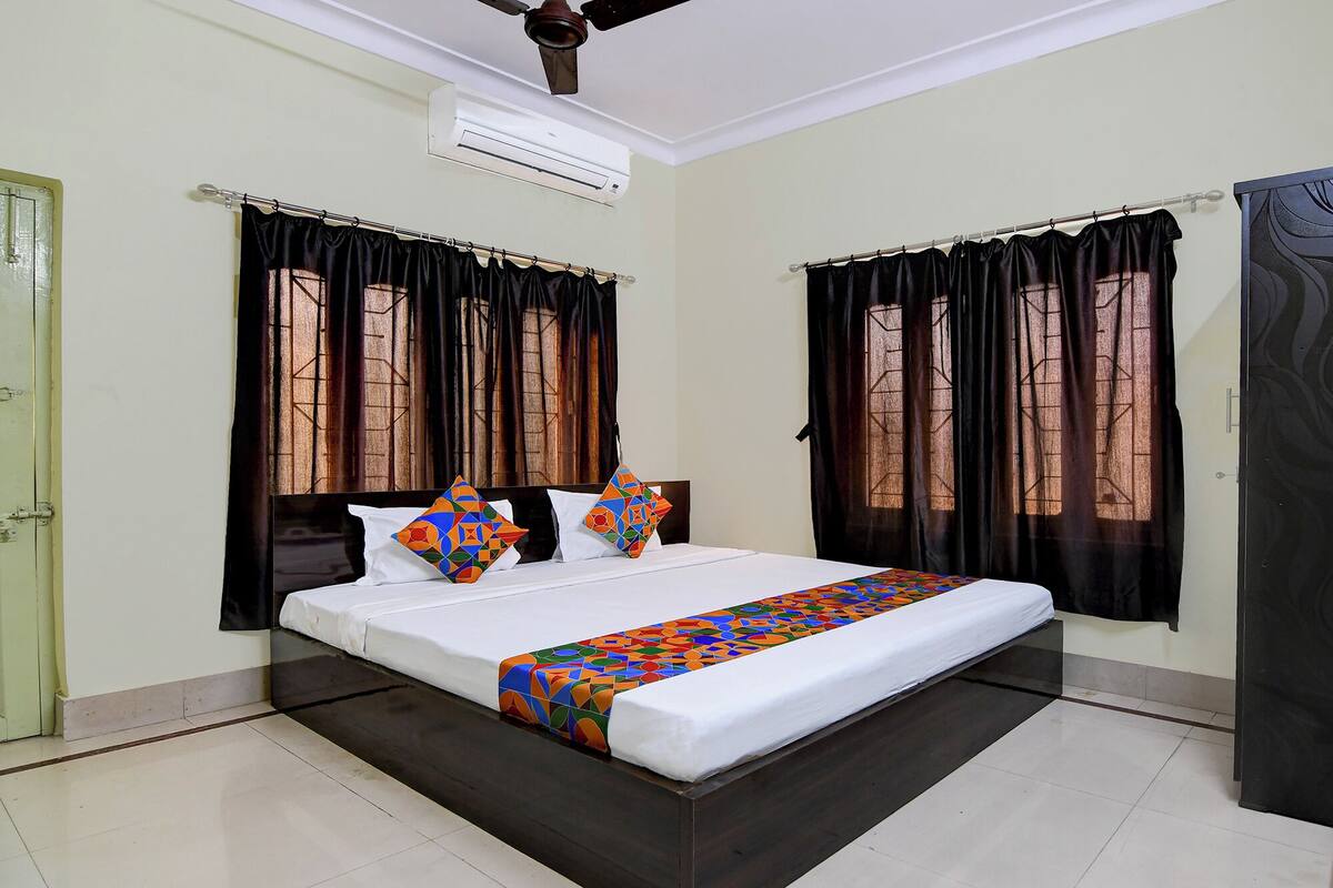 A bedroom with a large bed, black curtains, and a ceiling fan.