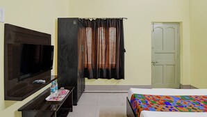 Habitación de hotel con cama, televisión, escritorio y un juego de botellas de agua, además de una puerta.