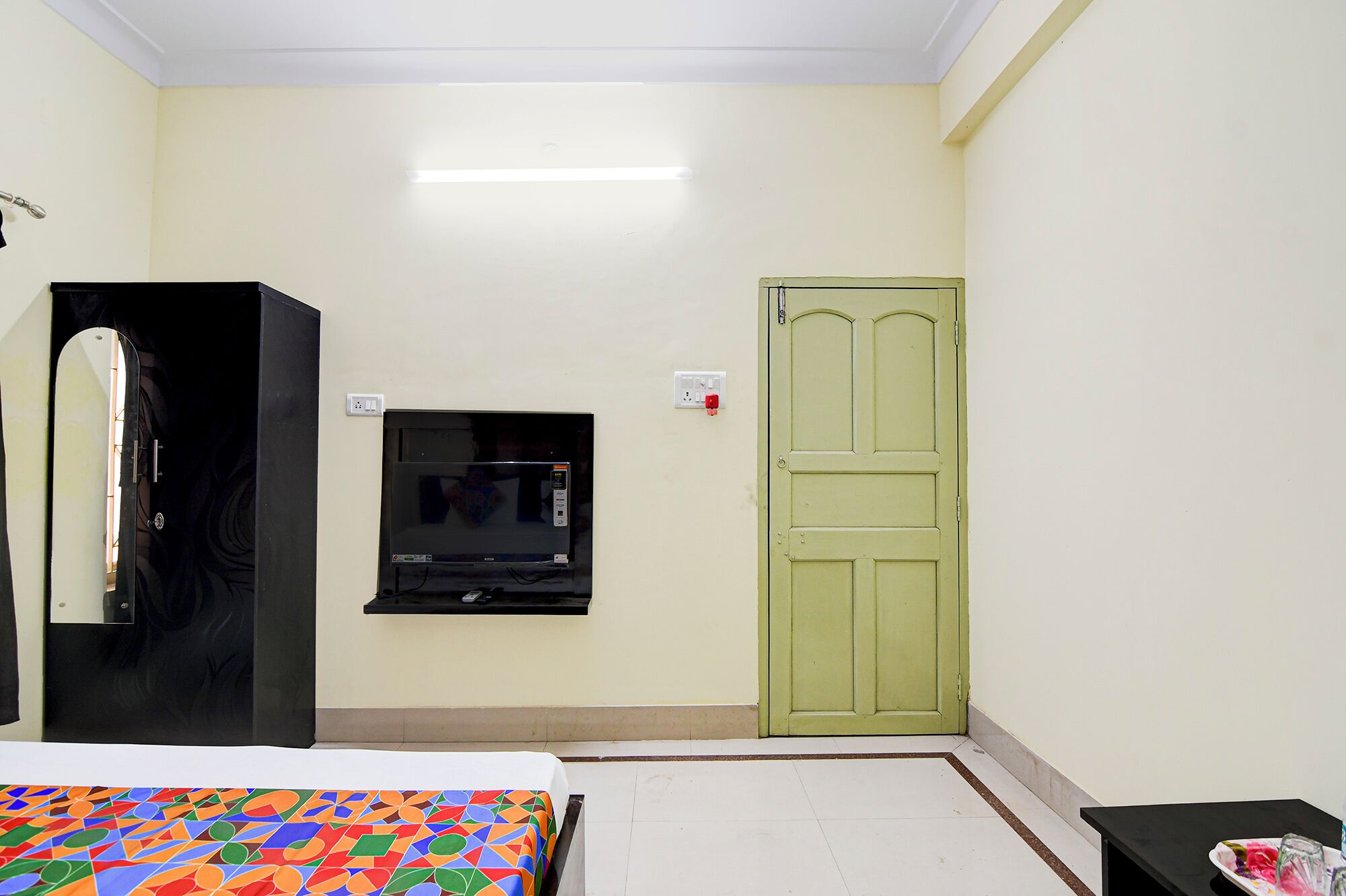 Une pièce comprenant un lit, un téléviseur fixé au mur, une armoire et une porte.