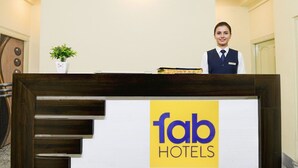 Una mesa de recepción con un letrero que dice "fab hotels" y una planta a la izquierda.