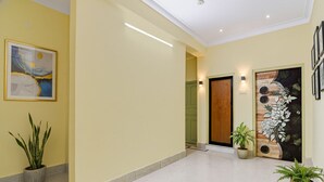 Un pasillo amplio con suelo de baldosas, una puerta de madera y una obra de arte colgada en la pared.
