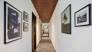 Un corridoio con opere d'arte incorniciate alle pareti, un soffitto in legno e un pavimento piastrellato.