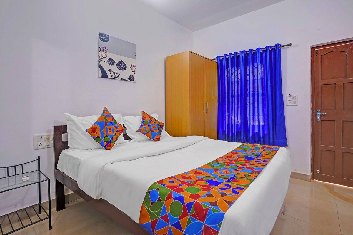 A bedroom with a bed, a wardrobe, a blue curtain, and a door.