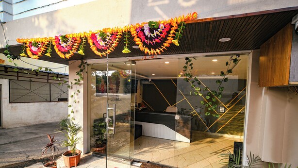 A hotel entrance with a glass door, a red mat, and potted plants. - Fabhotel Paradise Inn (Indore)