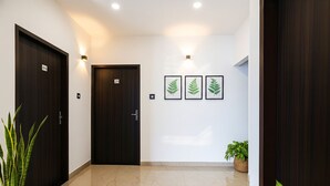 A hallway with two dark wooden doors, numbered 64 and 24, and three framed fern pictures on the wall. - Fabhotel Paradise Inn (Indore)
