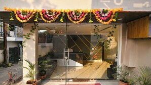 A hotel entrance with a glass door, potted plants, and a red mat. - Fabhotel Paradise Inn (Indore)