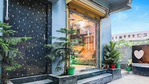 A building entrance with a dark door featuring star patterns, a glass door with a visible interior, and steps leading up to the entrance. - Fabhotel Love Birds Chinar Park (Barasat)