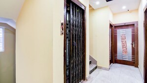 A hallway with a metal gate, a digital display, and a staircase leading to another room. - Fabhotel Love Birds Chinar Park (Barasat)