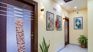 A hallway with a wooden door, a fire extinguisher, and a potted plant. - Fabhotel Love Birds Chinar Park (Barasat)