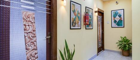 A hallway with a wooden door, a fire extinguisher, and a potted plant.