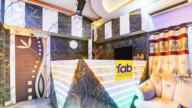 A hotel reception area with a modern design, featuring a marble reception desk, a clock, and a sofa. - Fabhotel Love Birds Chinar Park (Barasat)