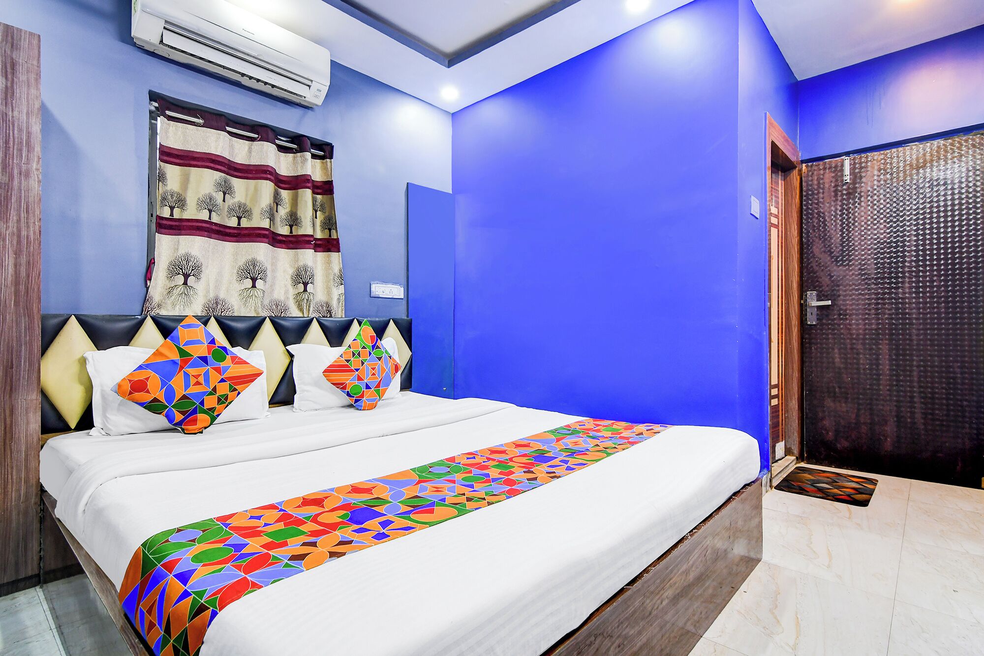 Ein Hotelzimmer mit einem Bett, einer blauen Wand, einer Klimaanlage und einer Tür.