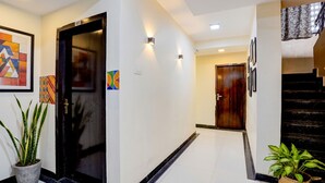 A hallway with a black door, a potted plant, and a staircase. - Fabhotel Chetan Executive (Pune)