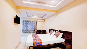 A bedroom with a bed, a ceiling fan, a window with curtains, and a flat-screen TV on the wall. - Fabhotel Chetan Executive (Pune)