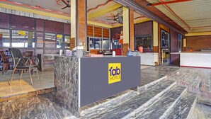 En hotellobby med en marmordisk, en skylt med texten ”fab hotels” och en trappa som leder upp till våningen ovanför.