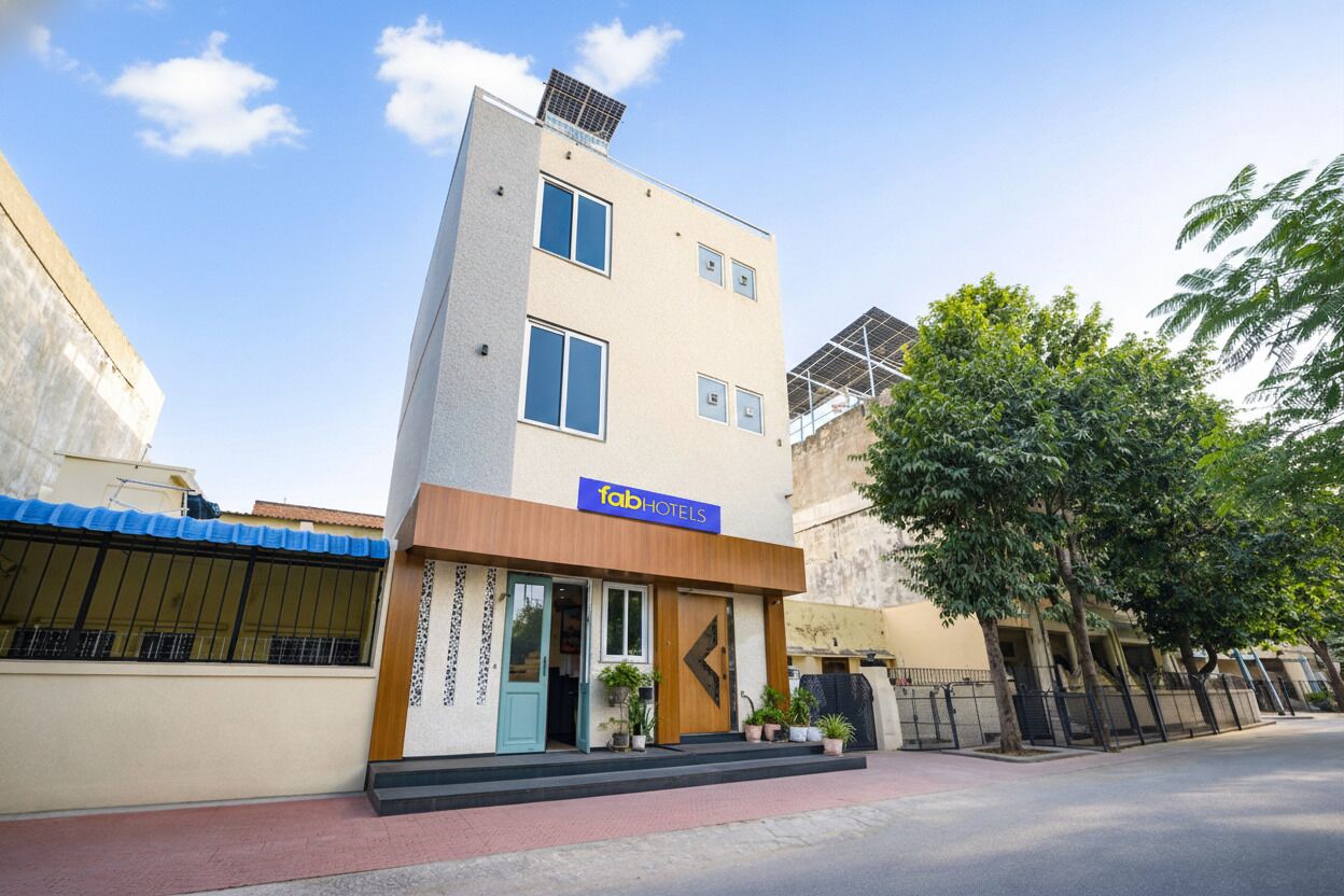 A modern building with a 'fab hotels' sign, featuring a flat facade, large windows, and a small entrance with potted plants.
