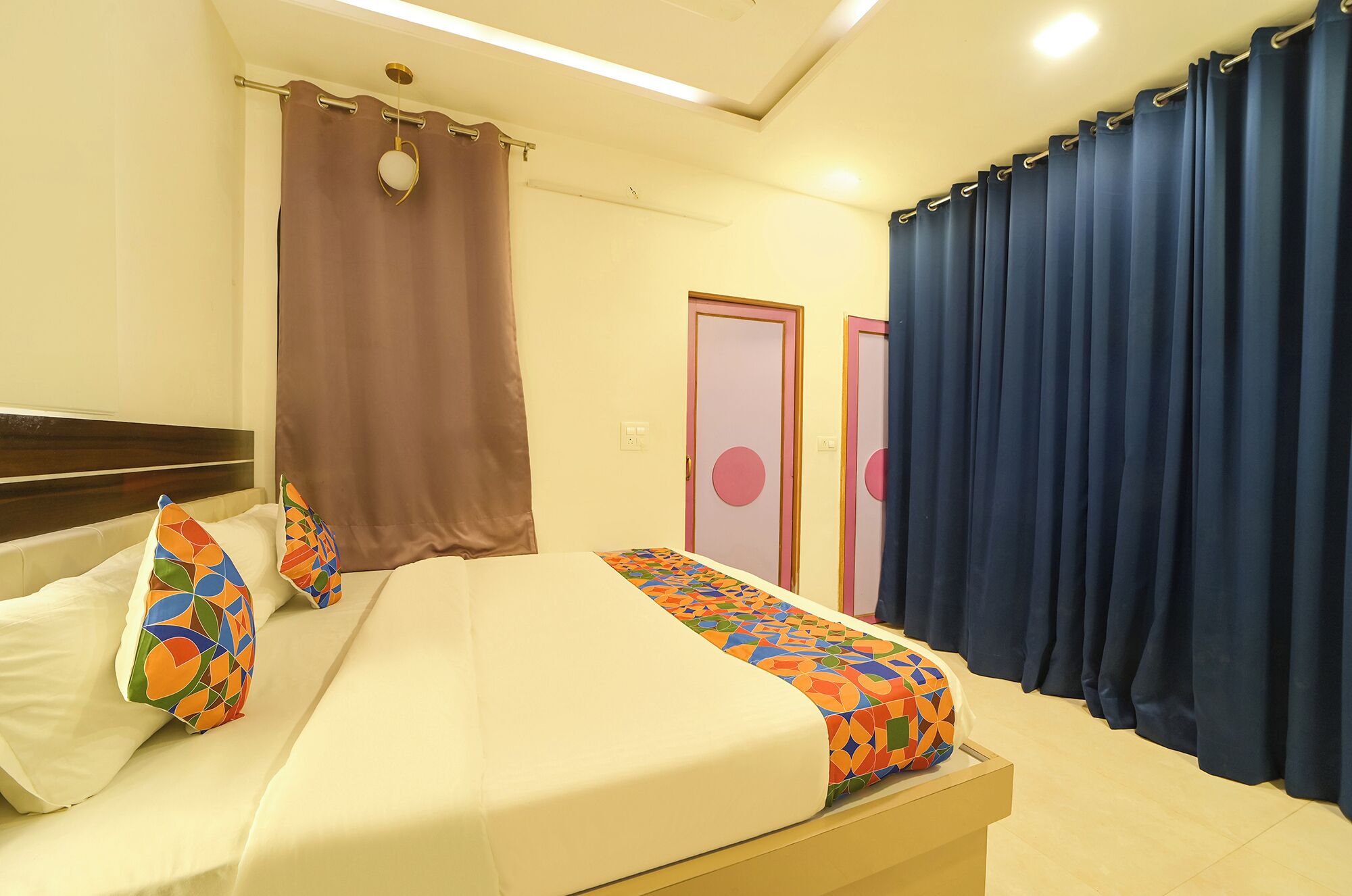 Une chambre d’hôtel comprenant un lit, une table de chevet, un miroir, une fenêtre avec des rideaux et une porte au motif circulaire.