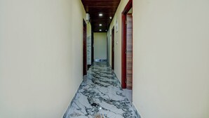 A hallway with marble flooring, wooden ceiling beams, and doors on both sides. - Via Aero Nest (Bengaluru)
