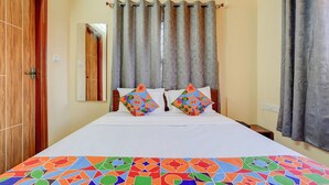 A hotel room with a bed, two pillows, a wooden door, a mirror, and grey curtains. - Via Aero Nest (Bengaluru)