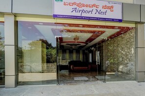 The entrance of a hotel named 'Airport Nest' with a glass facade and a red and gold interior design. - Via Aero Nest (Bengaluru)