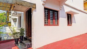 A building with a red-tiled entrance, a white exterior, and a small window with a grid pattern. - Via Fort Beach Residency (Kochi)