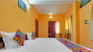A hotel room with a bed, a desk with a computer, and a window with curtains. - Via Fort Beach Residency (Kochi)