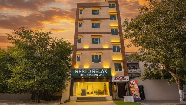 Ein mehrstöckiges Hotel namens Resto Relax mit modernem Design, das eine markante Fassade und ein Schild mit der Hotelwerbung aufweist.