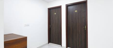 A room with two dark wooden doors, a marble-tiled floor, and a wooden cabinet.