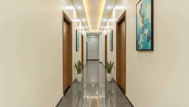 A modern hallway with a reflective floor, wooden doors, and potted plants. - Fabhotel Kesar Inn (Jaipur)