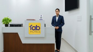 A hotel reception desk with a logo, a plant, a flat-screen TV, and a modern interior design. - Fabhotel Kesar Inn (Jaipur)