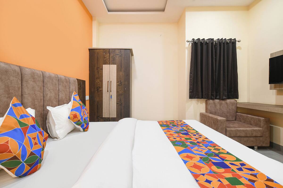 Une chambre d’hôtel avec un lit, une armoire, une chaise et un téléviseur.