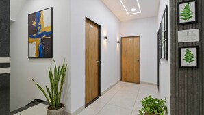 A modern hallway with wooden doors, a potted plant, and framed artwork on the walls. - Fabhotel Kavish Villa (Indore)