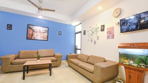 A living room with two sofas, a coffee table, a ceiling fan, a wall-mounted TV, and a fish tank. - Via KD6 Plaza Residency (New Delhi)