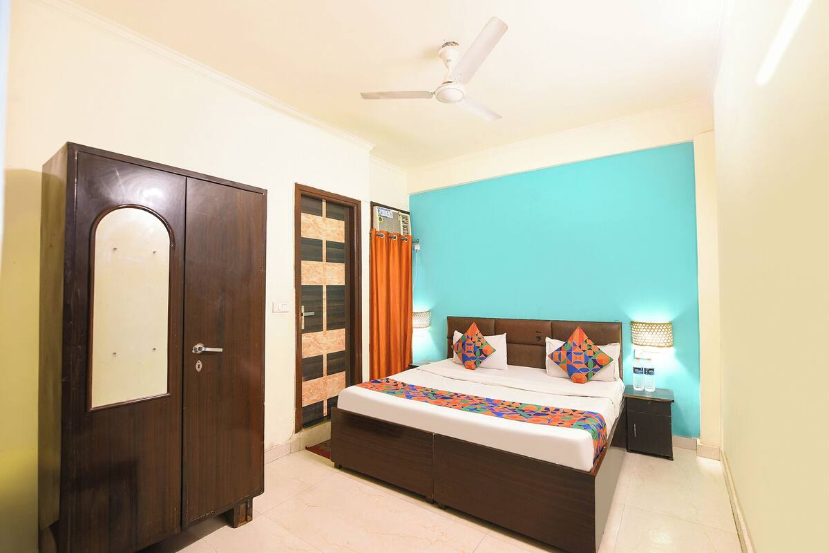 A bedroom with a bed, a wardrobe, a ceiling fan, and a window with curtains.