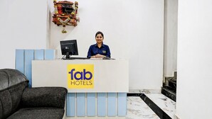 Een receptiebalie met het logo van Fab Hotels, een leren zwarte bank en een marmeren vloer.