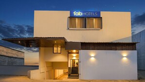 Een modern gebouw met een 'fab hotels' bord, een overdekte ingang en een trap naar de ingang.