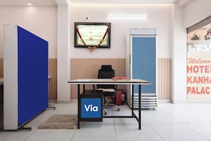 Zona de recepción de un hotel con mostrador, un cuadro en la pared, un panel azul y una puerta azul.