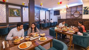 A restaurant with tables, chairs, and people dining. - Fabhotel The Glory (Rishikesh)