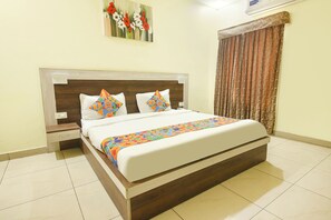 A hotel room with a bed, a nightstand, a wall-mounted air conditioner, and a window with curtains. - Fabhotel The Glory (Rishikesh)